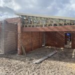 Under-construction SDA accommodation provider home with brick walls and timber roof frame.